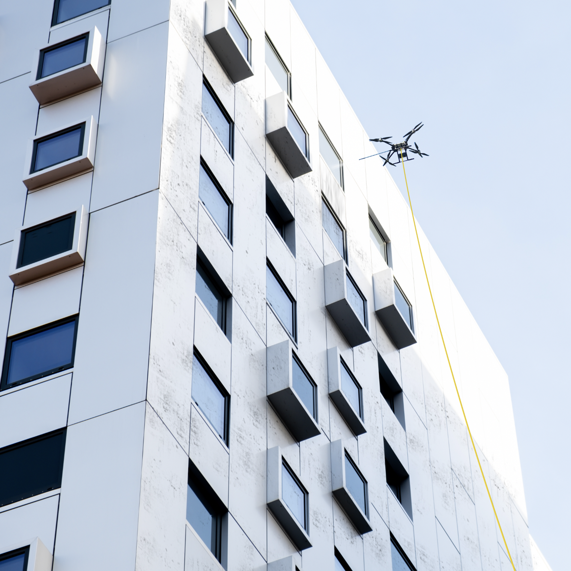 Drone cleaning image showing a power wash drone spraying water on an apartment building or block of flats exterior.